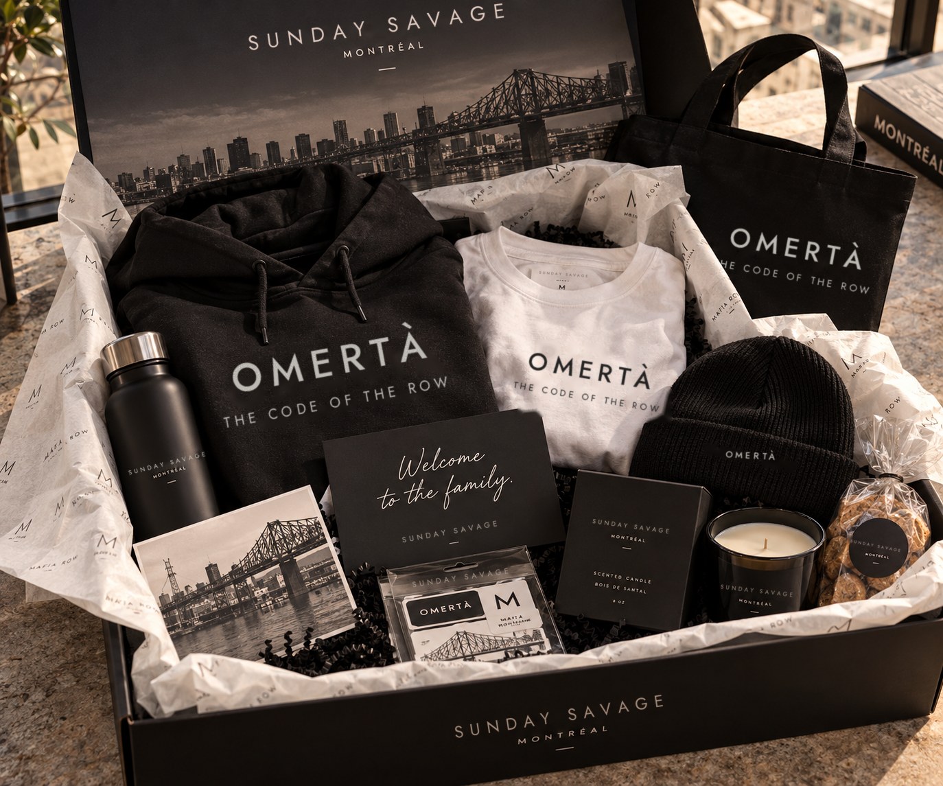 The Omertà gift set in its black Sunday Savage box: hoodie, tee, tote and beanie with a Welcome to the family card